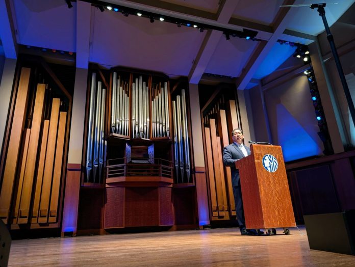 Mayor Bruce Harrell in front of Benaroya organ -Trumm 20250218 Harrell stands at a lectern with a big pipe organ behind him on the Benaroya auditorium stage.