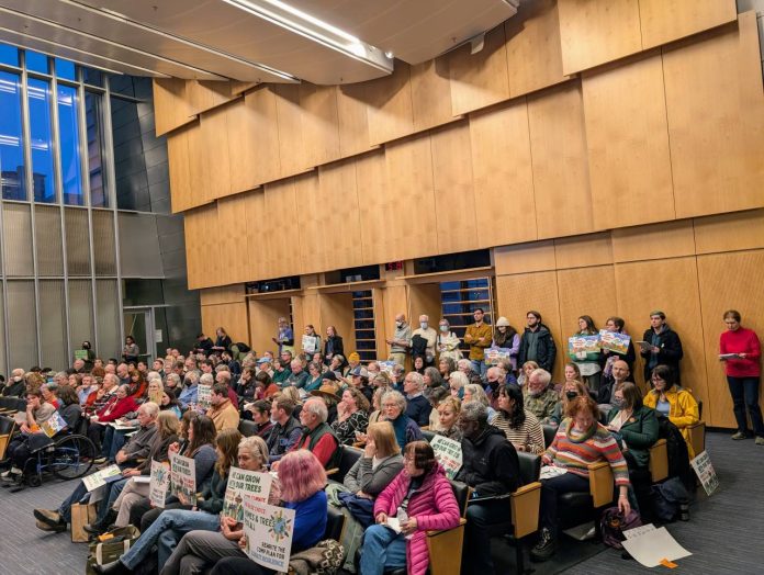 The Seattle Council Chambers crowd at One Seatlte 20250206 The Seattle council chambers are filled to the brim. People hold signs to promote their views.
