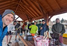 Eastside Coffee Outside: Brewing Community, One Cup at a Time a group of 15 people under a picnic shelter around a picnic with coffee and pastries on it