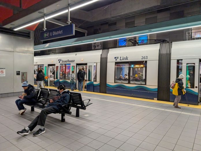 Some passengers catch a northbound train at U District Station while other wait on seats for the southbound.