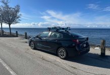 Op-Ed: Vancouver Shows Carshare’s Success Depends on Great Transit A black sedan is parked on the waterfront with the Evo logo displayed.