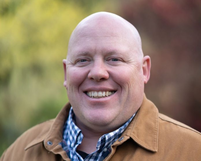 Jamie Headshot 1280px Jamie is a bald middle-aged man wearing a light brown coat.