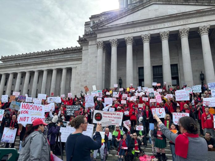 Hundreds of advocates hold signs on the steps of the Capitol Building.