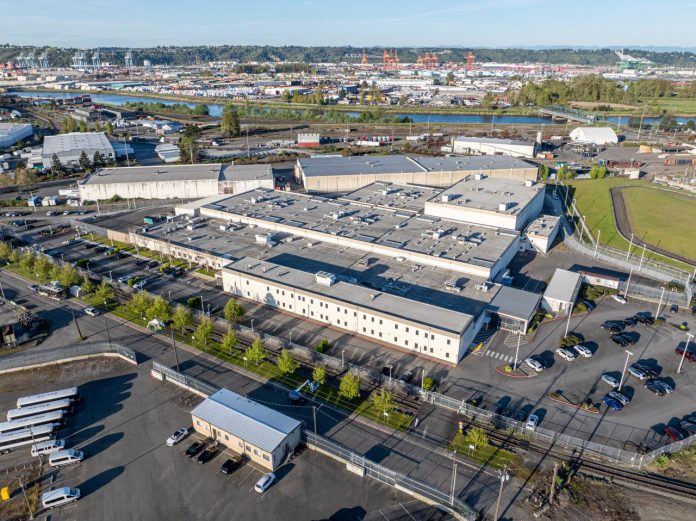 Tacoma Northwest ICE detention center The two-story detention center has white walls and is surrounded by asphalt parking.