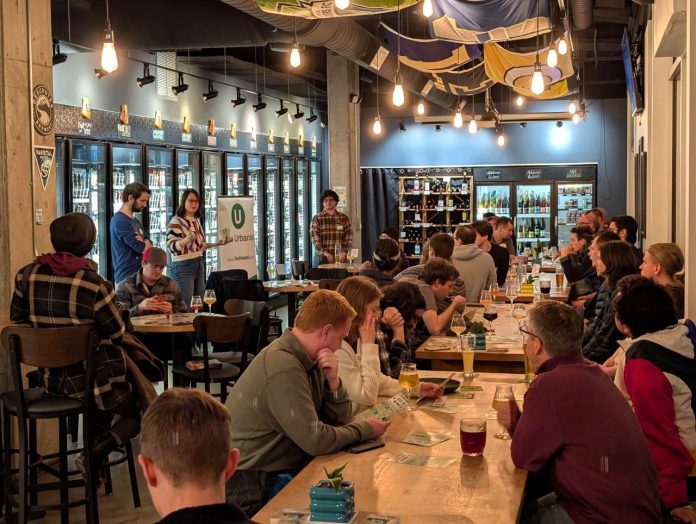 Attendees fill seats in long tables at Teku Tavern two members of House Our Neighbors present to the group.
