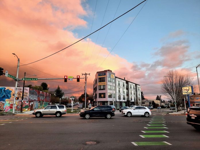 West Green Lake Aurora - Trumm 20211115 A five-story apartment building along Aurora Avenue with the sunset in the background.