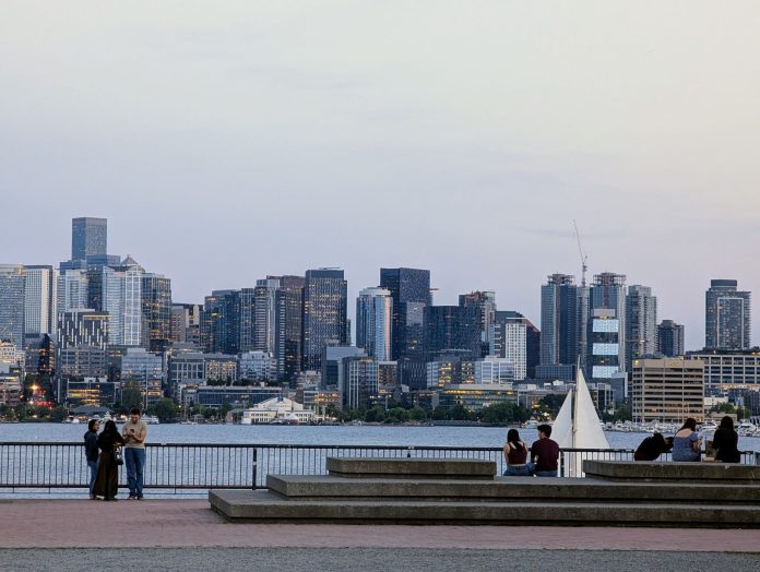 A sailboat passes in front of the seating area at Gas Works with the skyline in the distance