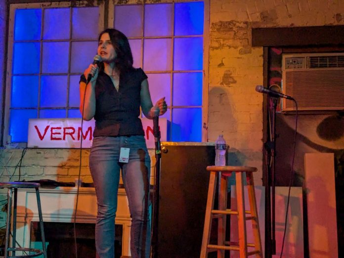 Rinck holds the mic on the Vermillion stage. She has long dark hair and a nose piercing.