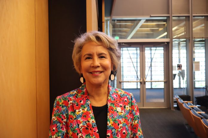 A native woman with grey hair wearing a loud, floral print suit