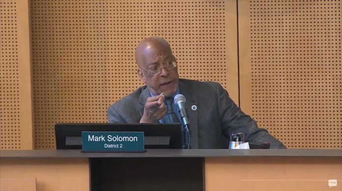 Mark Solomon housing committee Seattle Channel 2025-07-23 Solomon is a Black man wears a suit and glasses. He sits at the Council Chambers dais.