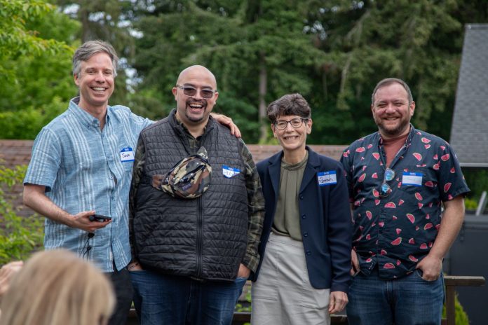 Burien Candidates via Devito Campaign 1600px The four candidate stand in a line smiling with trees in the background.