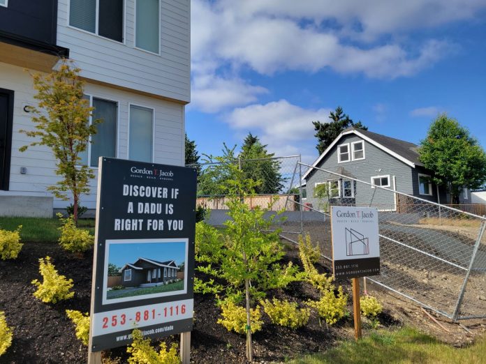 Discover ADU sign by Kevin Le 1280px A sign says "Discover if an ADU is right for you" in front of a home with a backyard cottage.