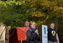 Wilson Maintains Lead over Harrell, Two New Polls Indicate Wilson holds a mic and two volunteers who banners for The Urbanist and for Seattle Tech4Housing.