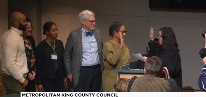 Lewis holds up her right hand to do the oath of office with a King County judge. Lewi's family is by her side.