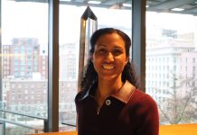 Dionne Foster Takes Office, Aiming to Tackle Housing Issues Foster smiles and stands in the atrium of Council Chambers with the south downtown skyline in the background.